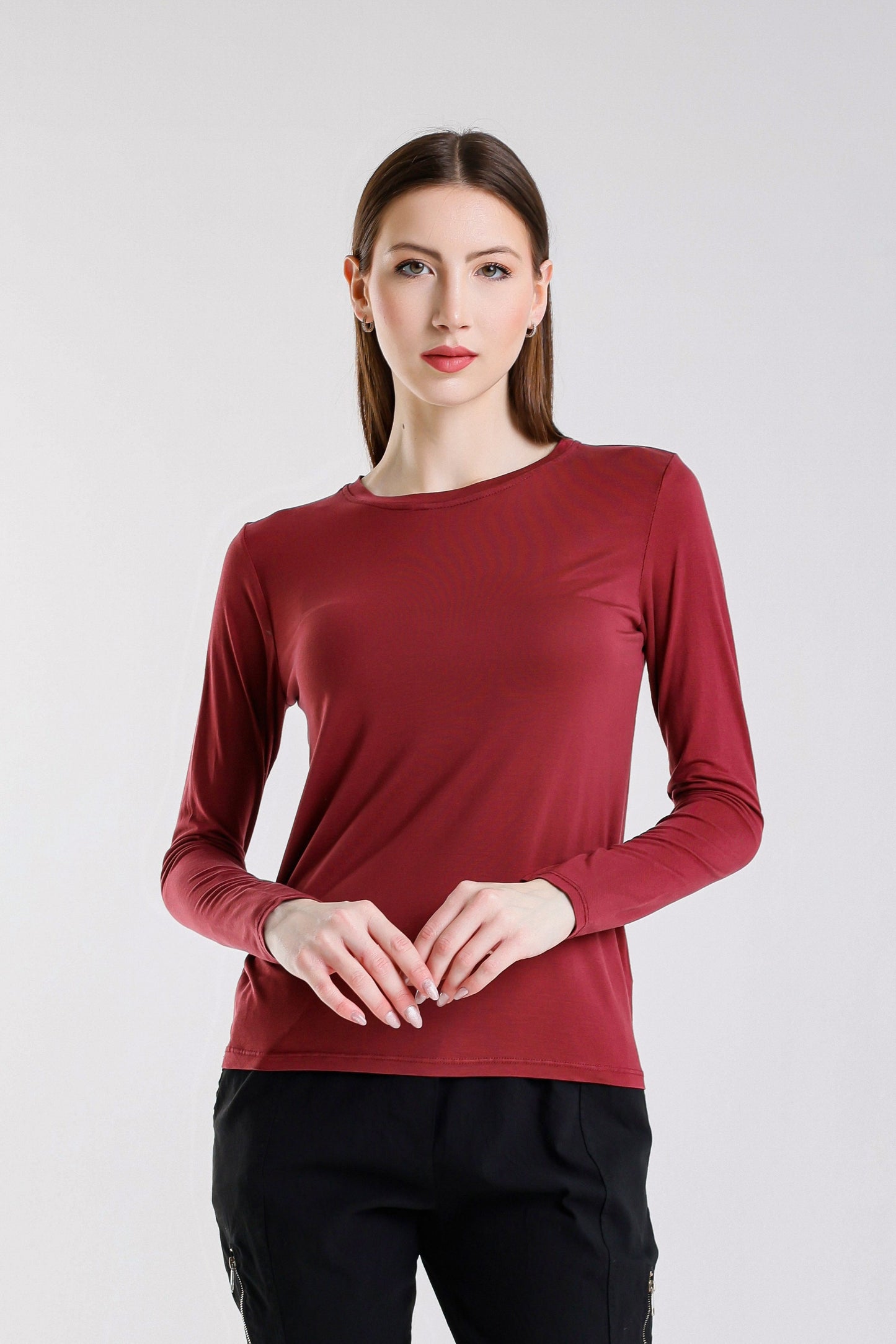 Woman wearing a red long-sleeve top against a white background